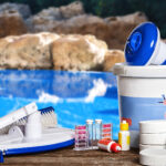 Pool chemicals and pool cleaning products next to a residential swimming pool